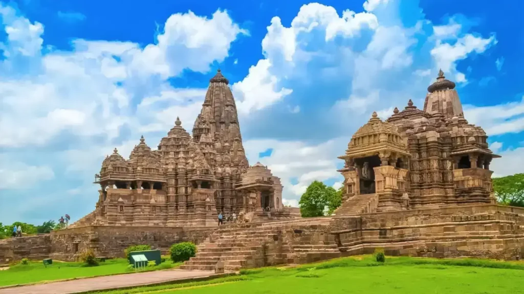 Kandariya Mahadev Temple, the largest temple in Khajuraho, showcases intricate stone carvings and stunning Nagara-style architecture under a bright blue sky.