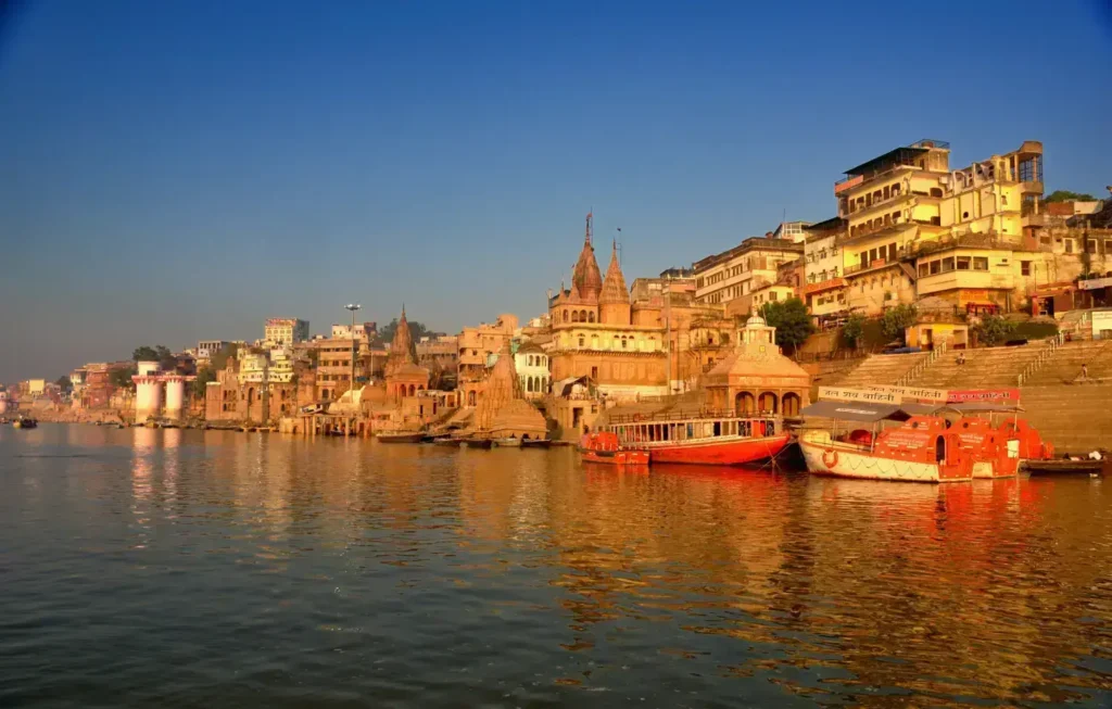 The serene ghats of Varanasi at sunrise, with historic temples, boats on the Ganges, and golden light reflecting on the water, capturing the city's spiritual essence.